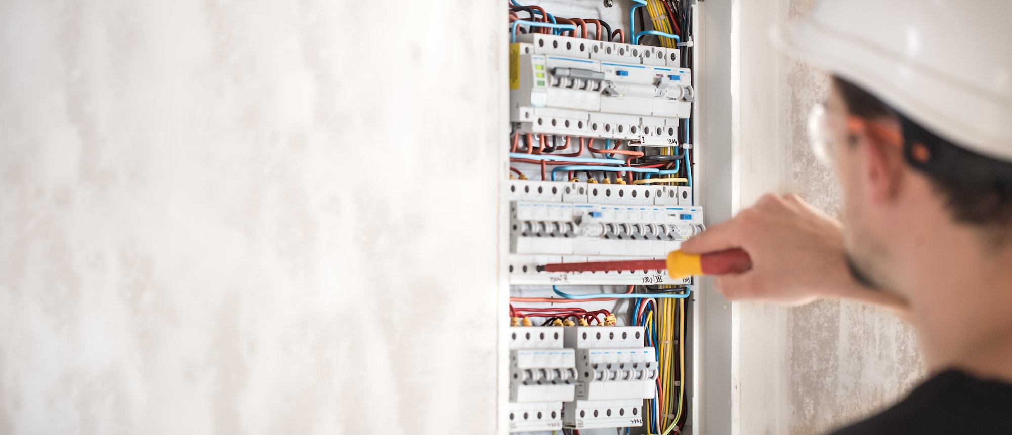 Man, an electrical technician working in a switchboard with fuses.